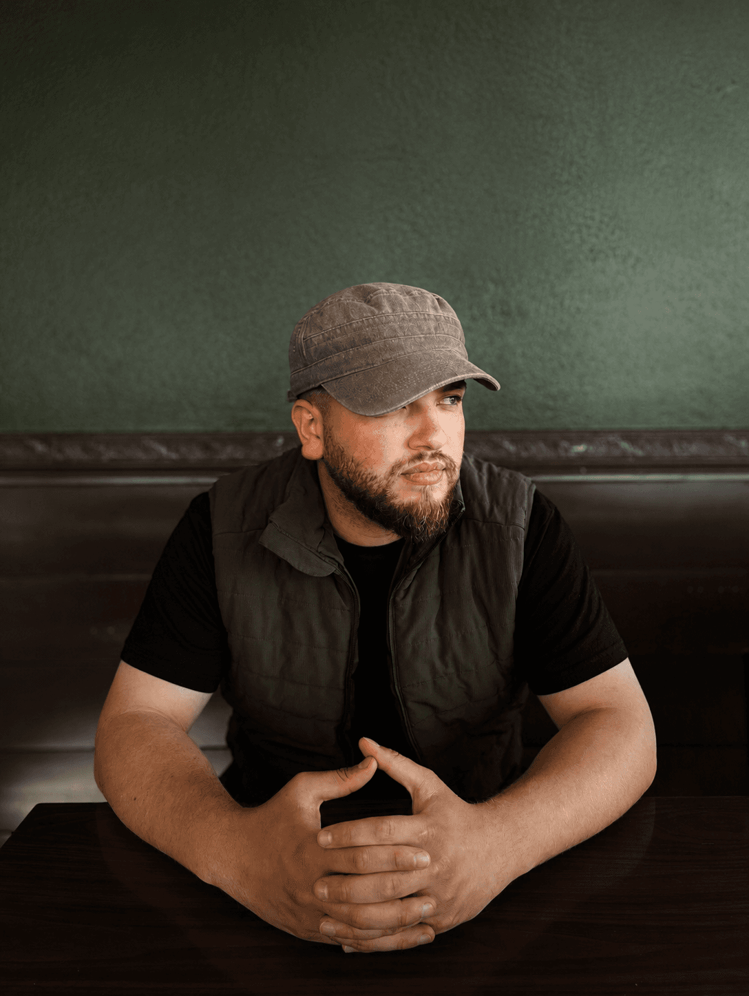 Founder seated in a café booth, looking thoughtfully to the side.